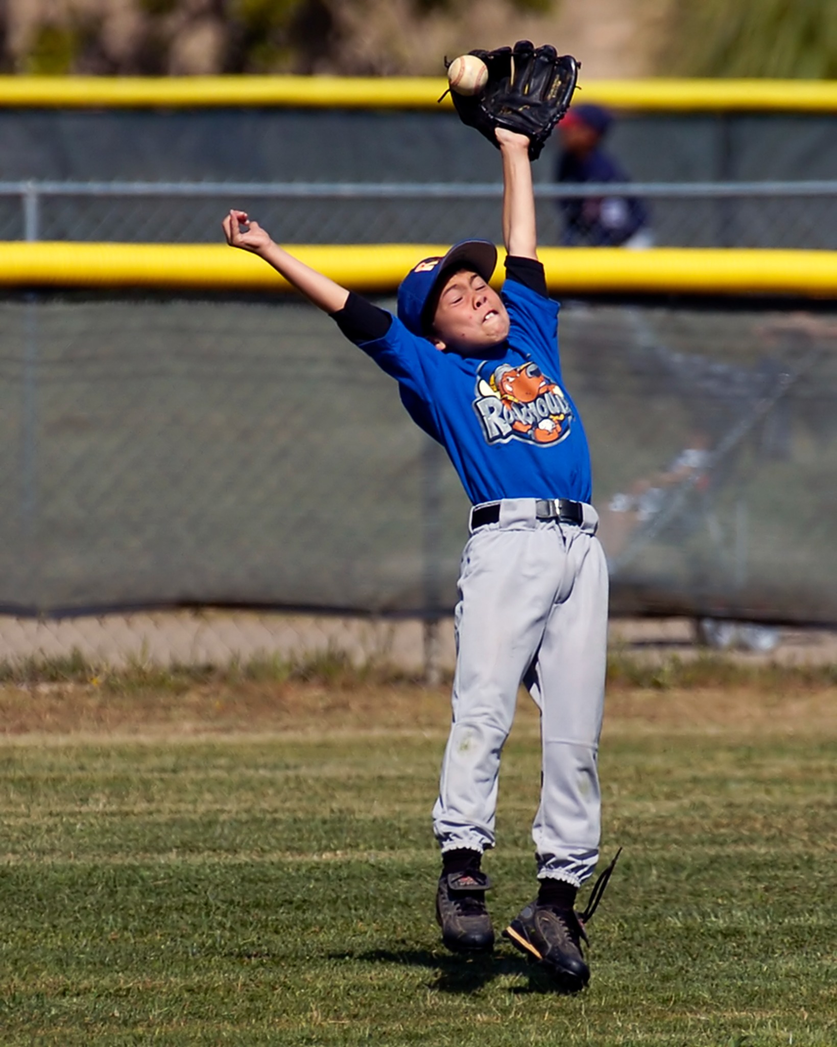 Youth baseball outfielder leaping with glove raised for a catch